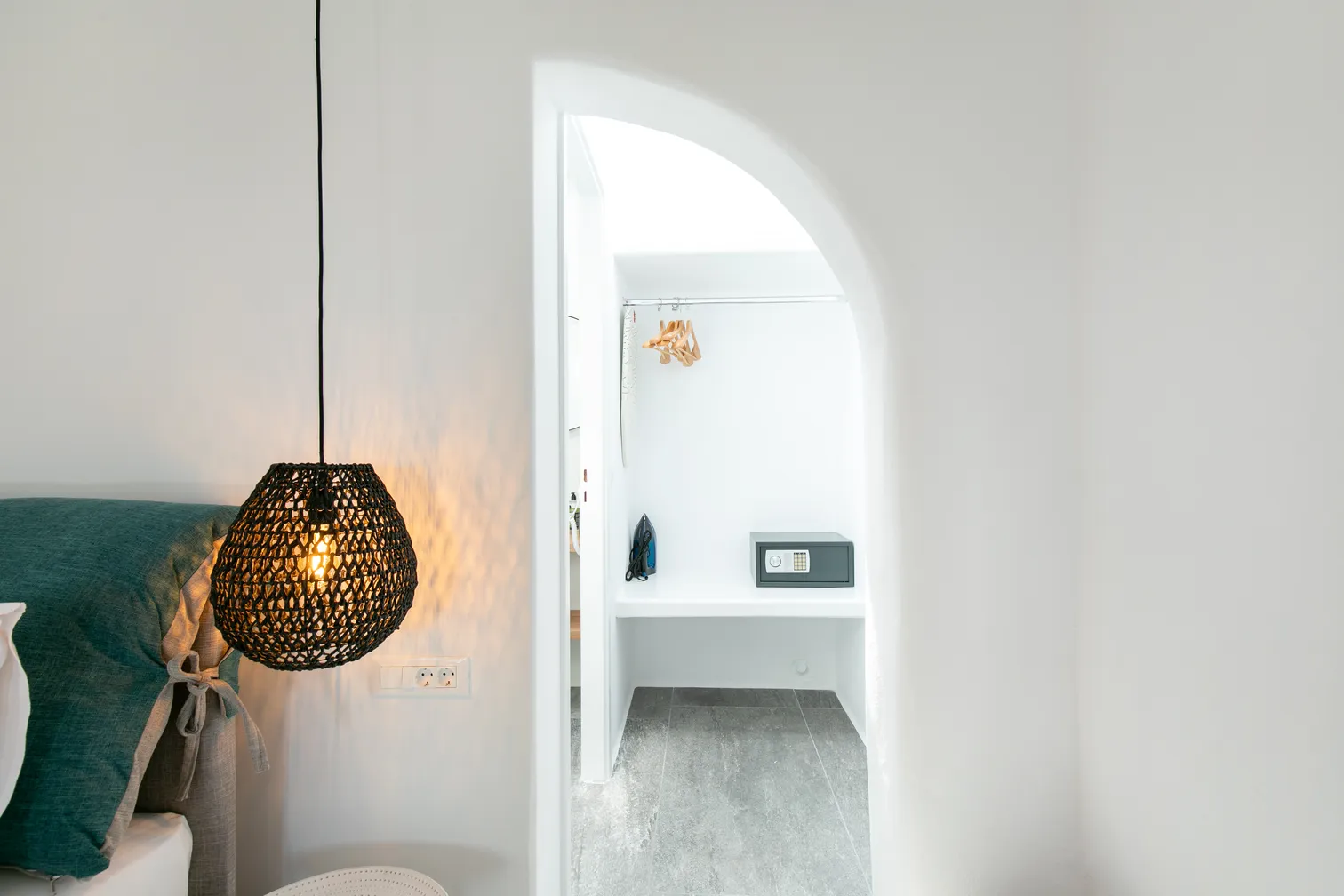 Rattan pendant lamp beside the bed and the arched doorway to the bathroom